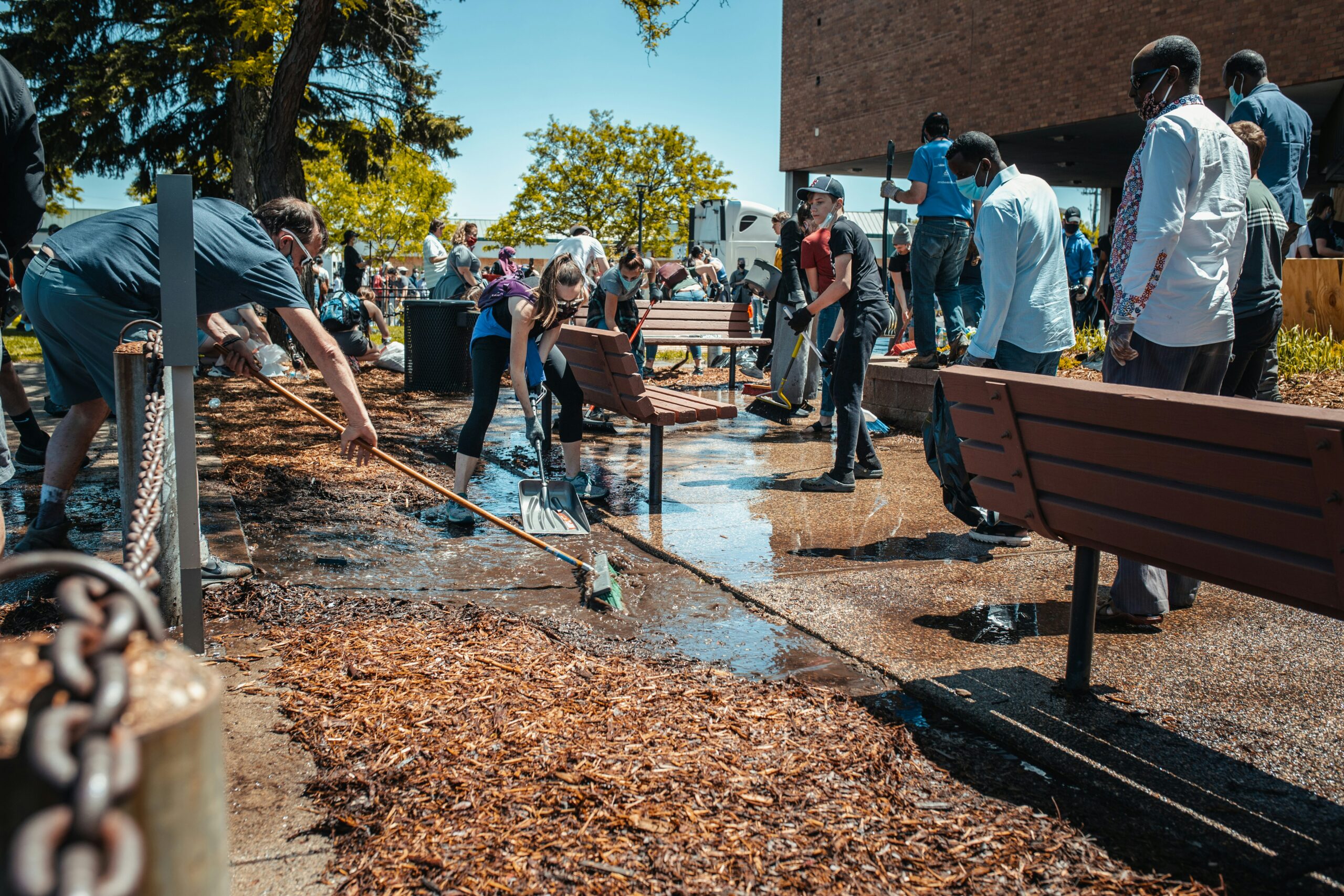 People cleaning up a walkway path next to a museum.