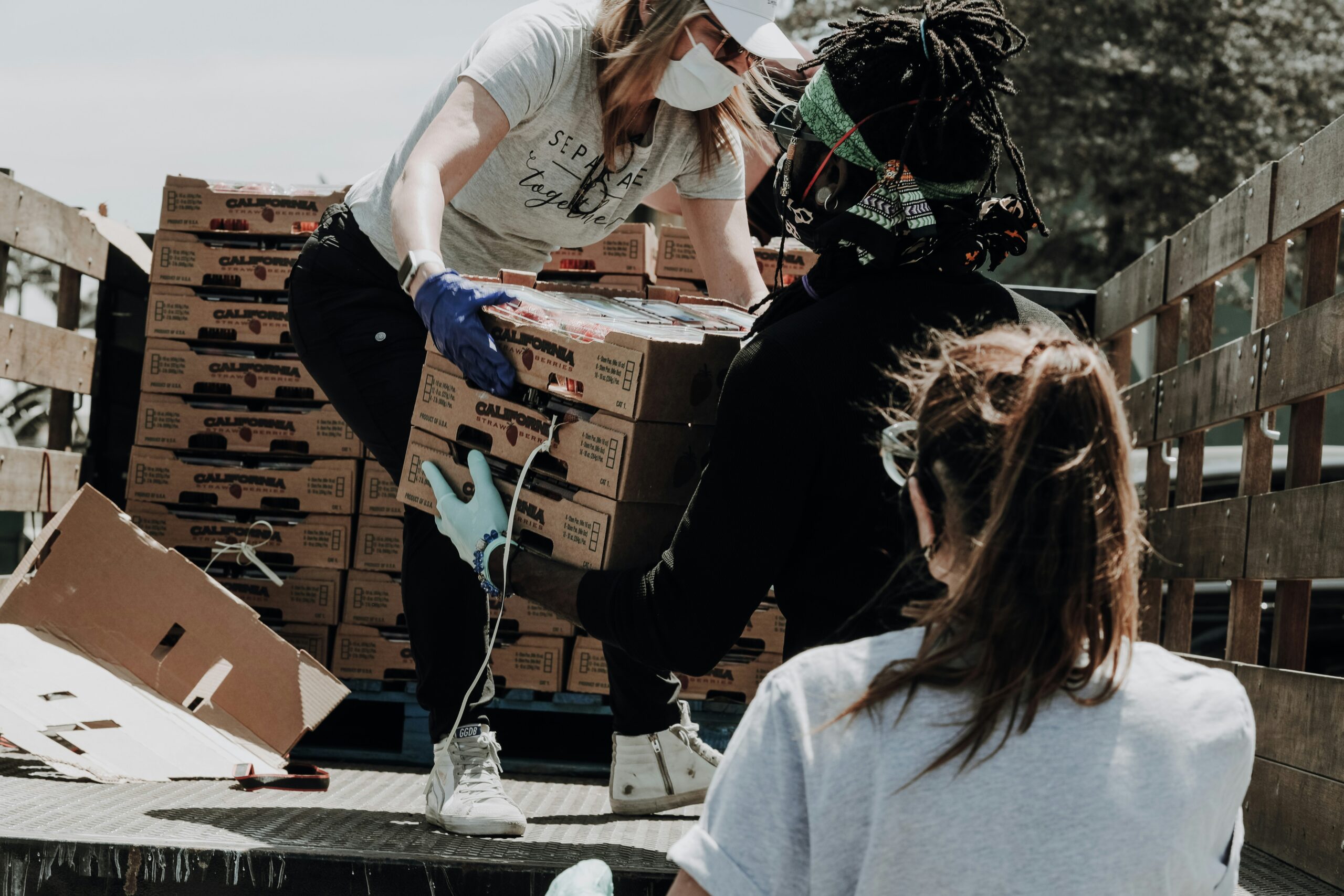 People picking up cases of food donations from the back of a flatbed truck.